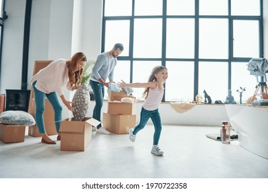 Happy Young Family Smiling And Unboxing Their Stuff While Moving Into A New Apartment