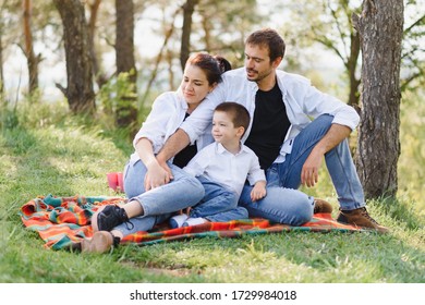 happy young family spending time outdoor on a summer day have fun at beautiful park in nature while sitting on the green grass. Happy family.