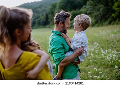 Happy Young Family Spending Time Together Outside In Green Nature.