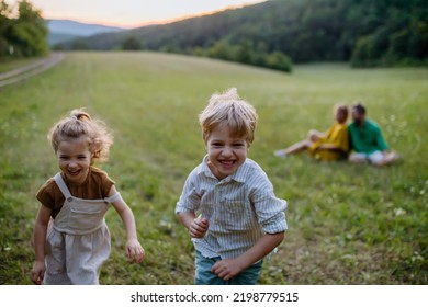 Happy Young Family Spending Time Together Outside In Green Nature.