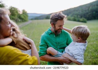 Happy Young Family Spending Time Together Outside In Green Nature.