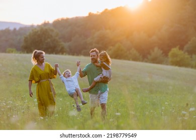 Happy Young Family Spending Time Together Outside In Green Nature.