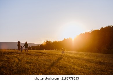 Happy Young Family Spending Time Together Outside In Green Nature.