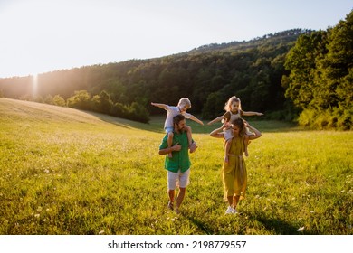 Happy Young Family Spending Time Together Outside In Green Nature.