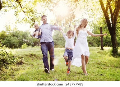 Happy Young Family Spending Time Together Outside In Green Nature.