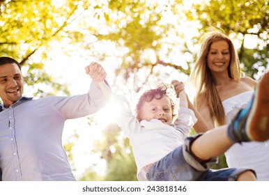 Happy Young Family Spending Time Together Outside In Green Nature.