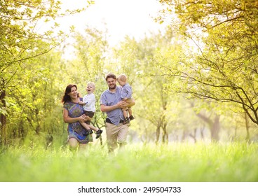 Happy Young Family Spending Time Together Outside In Green Nature.