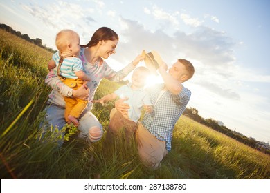 Happy Young Family Spending Time In The Park In Sunny Day (intentional Sun Glare, Lens Focus On Father)