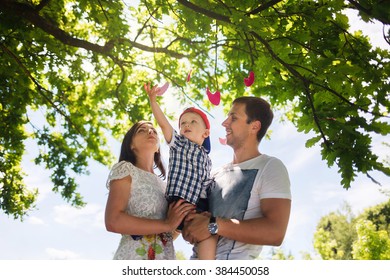 Happy Young Family Spending Time Together Outside In Green Nature