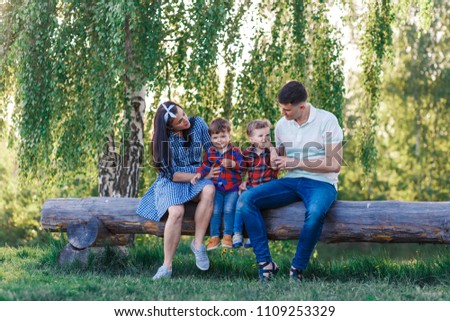 Happy young family spending time together outside in green nature near the wate. Parents playing with twins outside. Family of four walkng at the sunset hugging and having fun