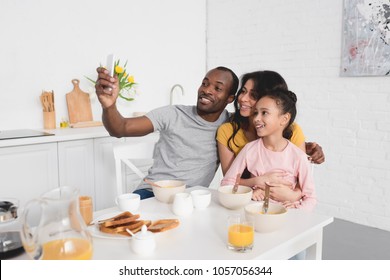 happy young family taking selfie on kitchen while having breakfast - Powered by Shutterstock