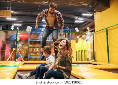 Happy young family with their little son jumping on a trampoline together at the entertainment centre