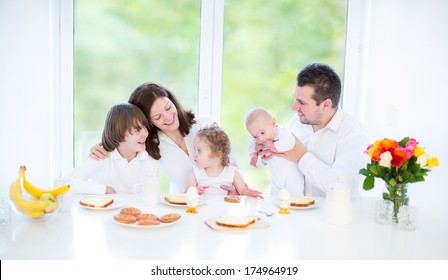 Happy Young Family With Three Children - Teenager Boy, Cute Toddler Girl And A Newborn Baby - Enjoying Breakfast In A White Sunny Dining Room With A Big Garden View Window