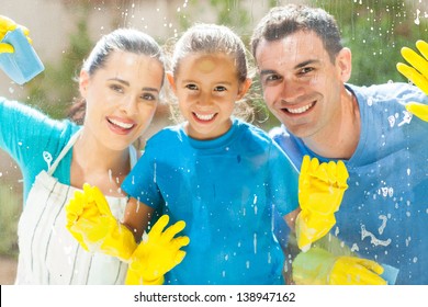 Happy Young Family Of Three Cleaning Home Window Glass Together