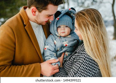 Happy Young Family Of Three In The Park On A Snowy Winter Day