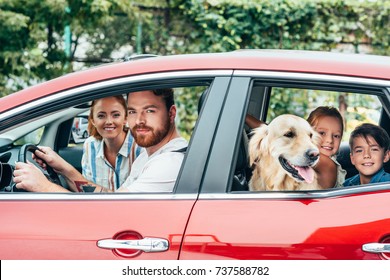 Happy Young Family Travelling By Car With Dog