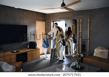 Happy young family with two children enetring room at luxury hotel, summer holiday.
