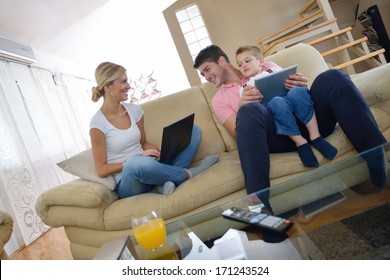 Happy Young Family Using Tablet Computer At Modern  Home For Playing Games And Education