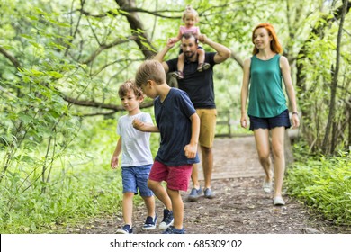 Happy Young Family Walking Outside In Green Nature