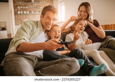 Happy young family watching a movie on the couch at home - Powered by Shutterstock