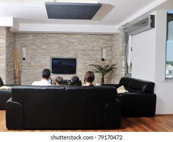 Happy Young Family Wathching Flat Tv At Modern Home Indoor