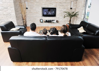 Happy Young Family Wathching Flat Tv At Modern Home Indoor