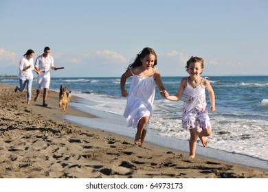 Happy Young Family In White Clothing Have Fun And Play With Beautiful Dog At Vacations On Beautiful Beach