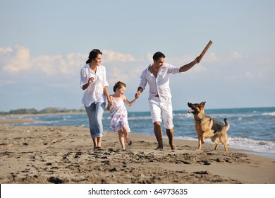 Happy Young Family In White Clothing Have Fun And Play With Beautiful Dog At Vacations On Beautiful Beach