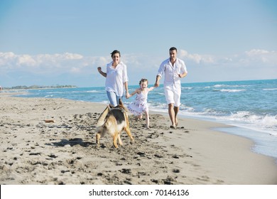 Happy Young Family In White Clothing Have Fun And Play With Beautiful Dog At Vacations On Beautiful Beach