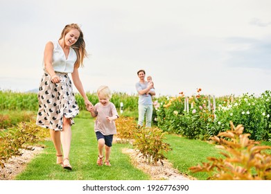 Happy young famuily with baby girl and toddler boy playing together on flower farm