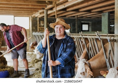 Happy Young Farmer Couple Working Inside Cowshed