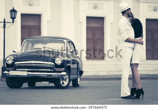 Happy\
young fashion couple in love next to retro\
car