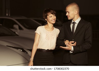 Happy Young Fashion Couple Walking On City Street At Night Stylish Man In Black Business Suit And Woman In Light Pink Blouse And Skirt