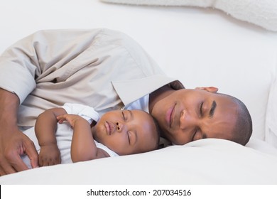 Happy young father with baby son on couch at home in the living room