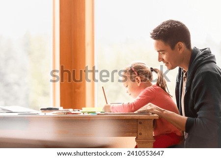 Happy young father and child at home learning writing doing homework 