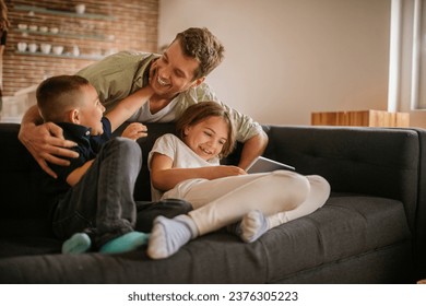 Happy young father having fun with his kids on the couch at home - Powered by Shutterstock