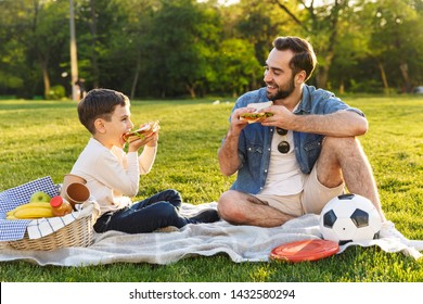 Happy young father having a picnic with his little son at the park, eating sandwiches - Powered by Shutterstock