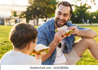 Happy young father having a picnic with his little son at the park, eating sandwiches - Powered by Shutterstock