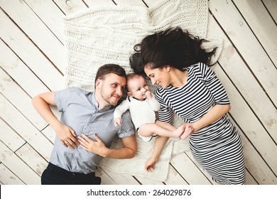Fröhlicher junger Vater, Mutter und süßer kleiner Junge auf rustikalem Holzboden