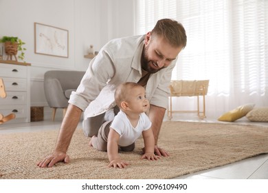 Happy young father watching his cute baby crawl on floor at home - Powered by Shutterstock