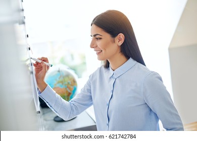 Happy young female business woman or teacher writing on white board with erasable marker - Powered by Shutterstock