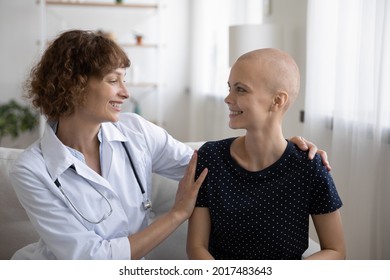 Happy Young Female Doctor Cuddling Shoulders Of Smiling Bald Woman Patient With Cancer Illness, Giving Psychological Support, Encouraging During Oncology Treatment, Sharing Good Treatment News.