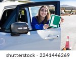 Happy young female driver showing her L sign lerner driving school in spain, ele autoescuela conductor novel