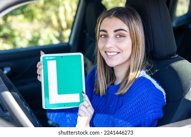 Happy young female driver showing her L sign lerner driving school in spain, ele autoescuela conductor novel