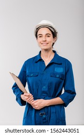 Happy Young Female Mechanic In Blue Workwear And Hardhat Holding Clipboard With Document While Standing In Isolation