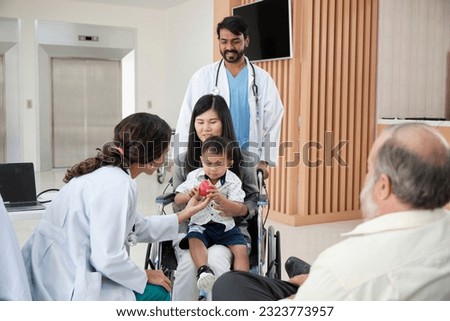 Happy young female pediatric doctor in uniform teasing little boy in wheelchair for medical exam at outpatient clinic hospital, people public health care checkup, and appointment visit.