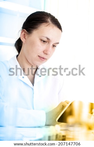 Happy young female researcher holding digital tablet in medical laboratory 