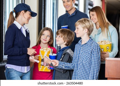 Happy Young Female Worker Checking Movie Tickets Of Family At Cinema