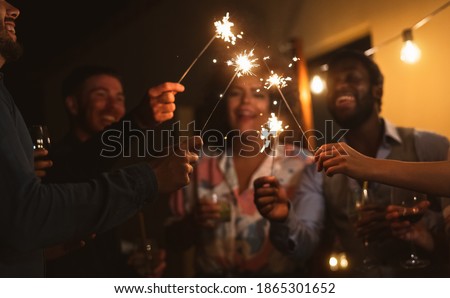 Happy young friends celebrating new year eve with sparklers fireworks and drinking cocktails on patio house party - Youth people lifestyle and holidays concept - Soft focus on hand