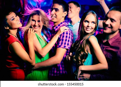Happy young friends dancing at disco